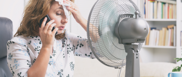 woman sitting at her work desk with fan blowing in face