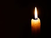 Burning candle isolated against a black background