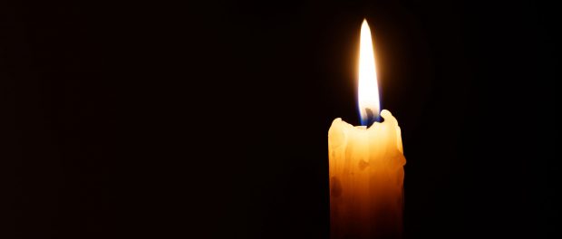 Burning candle isolated against a black background