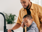 kid doing the dishes with his dad