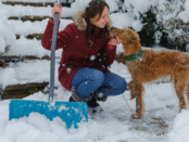 woman shoveling with her dog